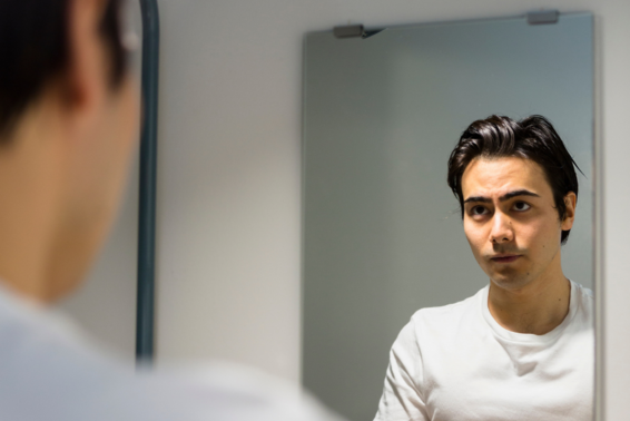 Young man looking at himself in a mirror