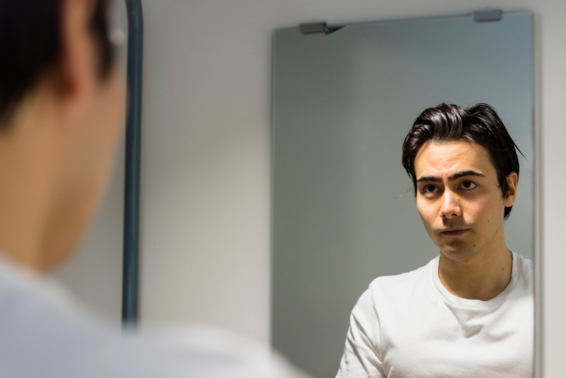 Jeune homme qui se regarde dans un miroir